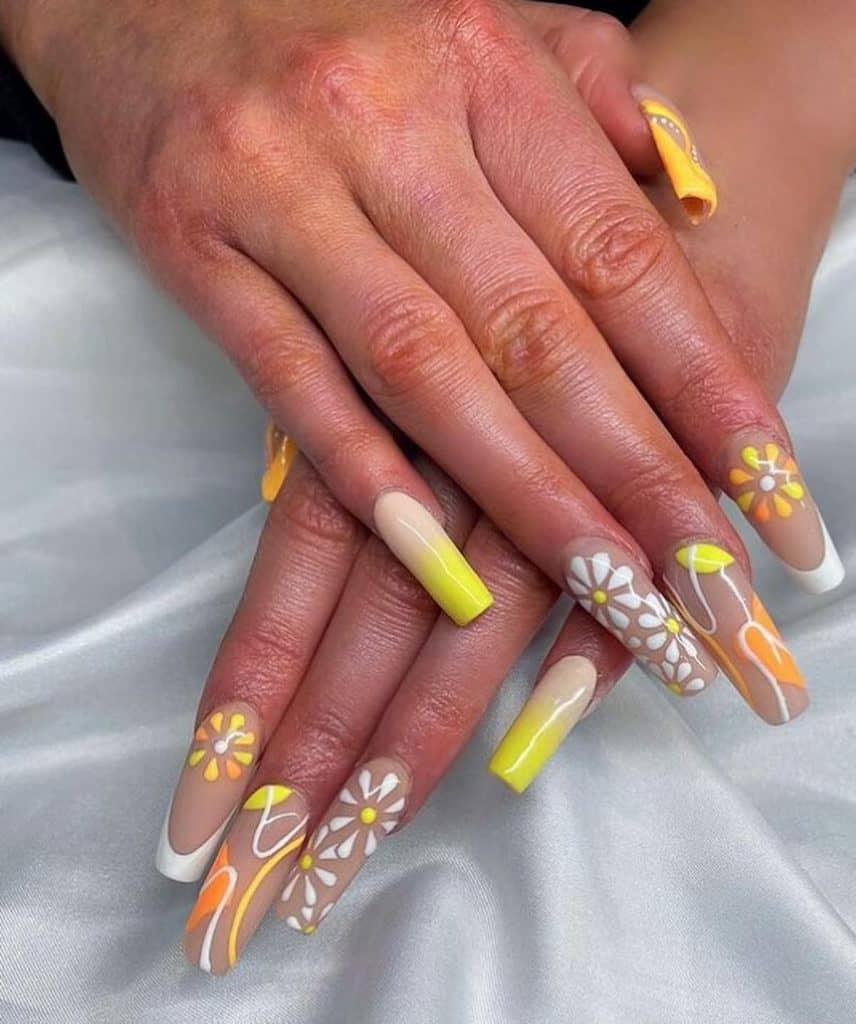Manos de mujer con una hermosa combinación de esmalte de uñas nude, amarillo, naranja y blanco que tiene flores, hojas y patrones ondulados.