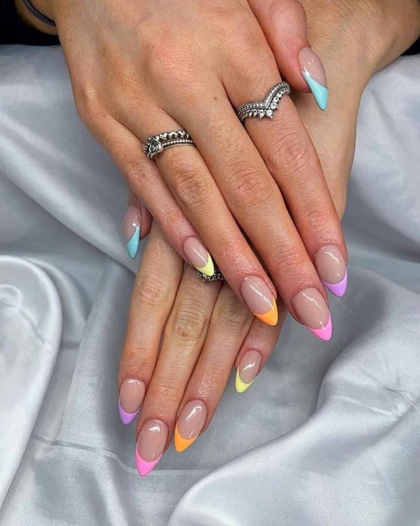 Las manos de una mujer con un hermoso esmalte de uñas nude que tiene puntas de uñas de colores brillantes.